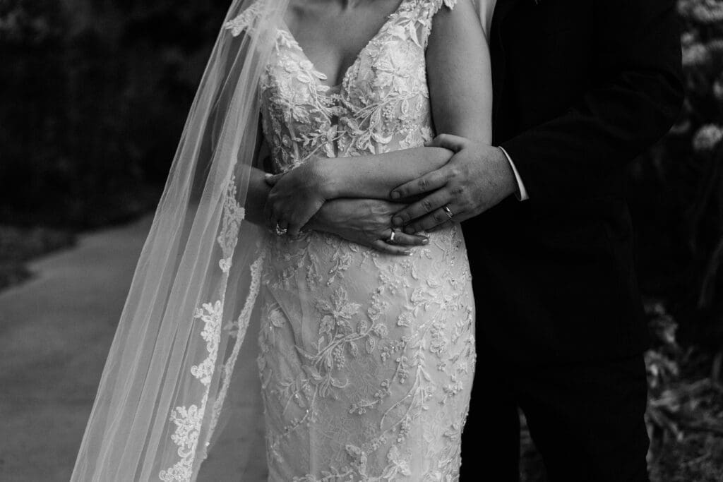 A black and white photo of a bride and groom holding each other, which their wedding rings being the primary focus, taken by an Asheville Elopement Photographer