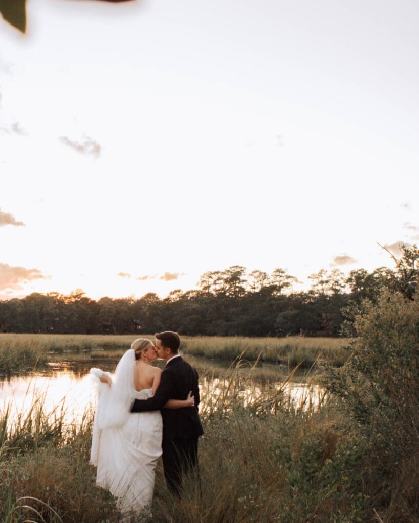 An eloping couple kiss in the sunset in front of a lake in a South Carolina Park