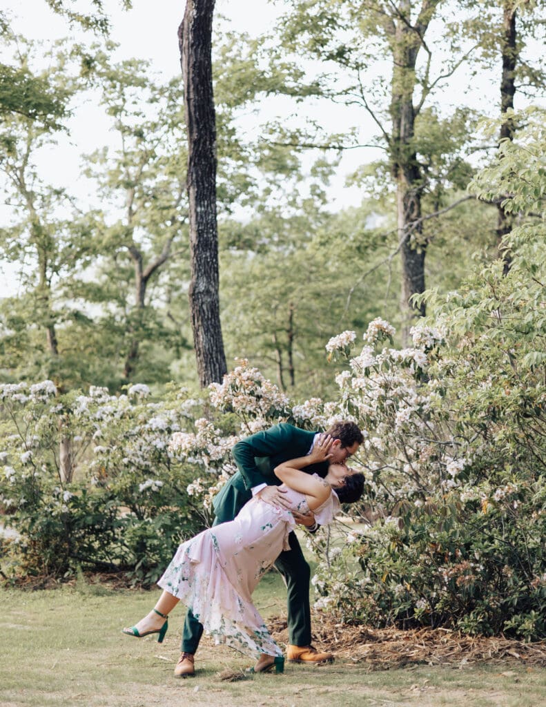 A groom dips his bride in front of South Carolina Mountain laurels.