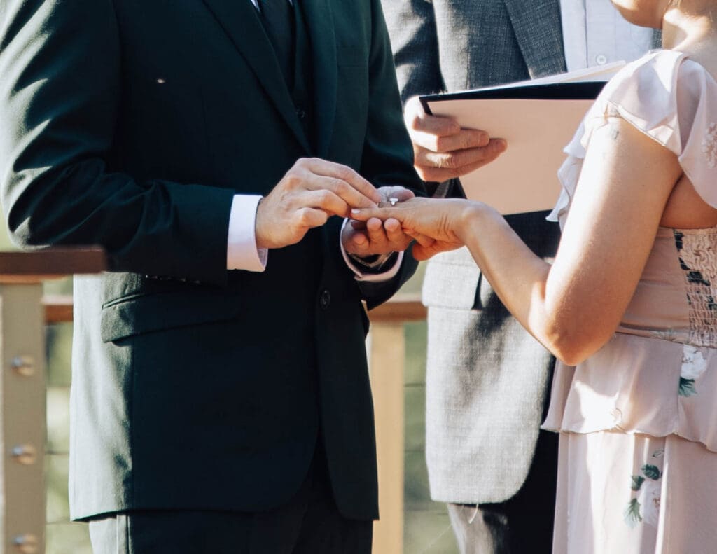A groom placing a ring on the bride's finger.