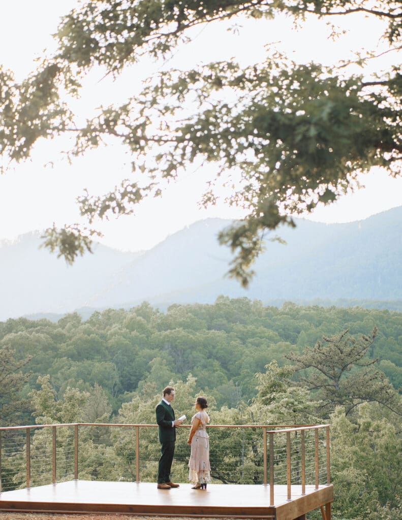 A bride and groom say their vows with the Carolina mountains behind them.